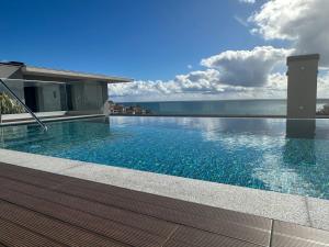 a swimming pool on top of a building with the ocean at Deluxe Bay View in Câmara de Lobos