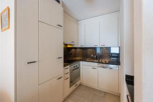 a kitchen with white cabinets and a sink at CASA BELLINA in Davos +11 photos