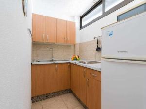 a kitchen with wooden cabinets and a sink and a refrigerator at Marlenghi Apartments 818 in San Bartolomé