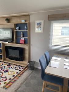 een woonkamer met een televisie en een tafel en stoelen bij Dave and Deb's Place Beverley Bay in Paignton