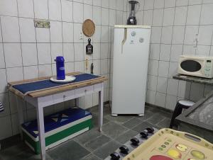 a kitchen with a refrigerator and a table and a microwave at "Nossa Casa Da Praia" Peruíbe SP in Peruíbe +60 photos