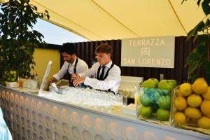 two men are standing behind a buffet of fruit at Grand Hotel San Lorenzo in Mantova