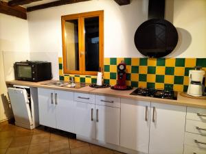 a kitchen with white cabinets and a sink and a microwave at GITE LE MONTENEY in Pont-Audemer