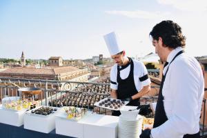 zwei Männer stehen auf einem Balkon mit Tisch und Essen in der Unterkunft Grand Hotel San Lorenzo in Mantua