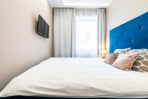 een slaapkamer met een groot wit bed met een blauw hoofdeinde bij Apartament Arena Gliwice Budget in Gliwice