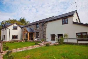 Pen y ClawddにあるBentra - Boutique Cottage at Harrys Cottagesの緑の庭のある大きな白い家