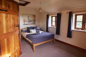 - une chambre avec un lit et 2 fenêtres dans l'établissement Bentra - Boutique Cottage at Harrys Cottages, à Pen y Clawdd