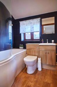 La salle de bains est pourvue de toilettes, d'une baignoire et d'un lavabo. dans l'établissement Bentra - Boutique Cottage at Harrys Cottages, à Pen y Clawdd