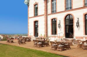 une terrasse avec des tables et des chaises dans un bâtiment dans l'établissement Chateau de Sacy, à Sacy