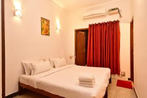 een slaapkamer met een bed met een rood gordijn bij Villa Felicia in Pondicherry