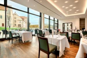 een restaurant met witte tafels en stoelen en grote ramen bij Boardinghouse My Maison in Morschen