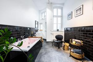 a bathroom with a pink tub and black tiles at LivingRoom 2 z wanną z hydromasażem in Katowice +16 photos