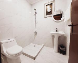 a white bathroom with a toilet and a sink at De Iris Regency Fahaheel in Kuwait