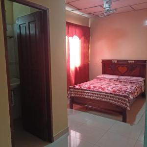 Schlafzimmer mit einem Bett mit einer roten Tagesdecke in der Unterkunft HOTEL PRIMAVERA in Guayaquil