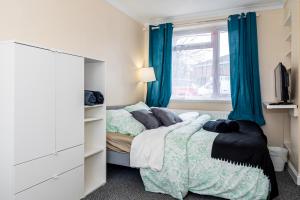 1 dormitorio con 1 cama y una ventana con cortinas azules en Shirley House 3, Guest House, Self Catering, Self Check in with Smart Locks, Use of Fully Equipped Kitchen, close to City Centre, Ideal for Longer Stays, Walking Distance to BAT, 20 min Drive to Fawley Refinery, Excellent Transport Links en Southampton