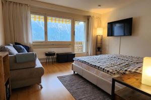 1 dormitorio con cama, sofá y TV en Retreat SoloHike en Mörel