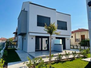 a white house with a tree in front of it at GEMINI VILLAS NIKITI in Nikiti