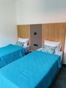 two beds in a hotel room with blue sheets at GEMINI VILLAS NIKITI in Nikiti