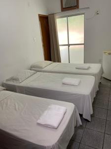 three beds in a room with white sheets and towels at Granvalle Hotel Juazeiro in Juazeiro