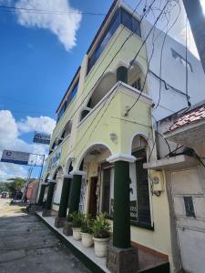 ein Gebäude mit grünen Säulen vor einer Straße in der Unterkunft Nakum Hotel in Flores