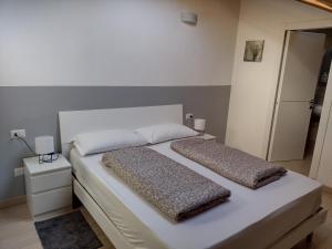 uma cama branca com duas almofadas em cima em Casa Terrazzo Panoramico em Cannobio