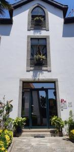 a white building with a door and windows and potted plants at Residencialusobrasileira in Leça da Palmeira