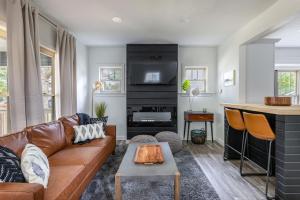 a living room with a brown leather couch and a fireplace at The Akron Retreat: Modern 3-Bedroom Oasis in Akron