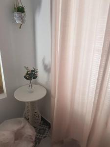 un tavolo bianco con un vaso di fiori sopra accanto a una tenda di Casa Rural Los Naranjos a Constantina