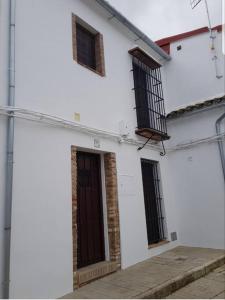 um edifício branco com janelas com barras e uma porta em Casa Rural Los Naranjos em Constantina