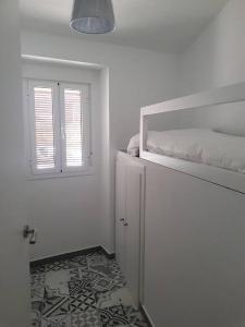 um quarto branco com uma cama e uma janela em Casa Rural Los Naranjos em Constantina