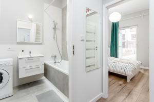 a white bathroom with a tub and a sink at Chill Apartments Marywilska in Warsaw +99 photos