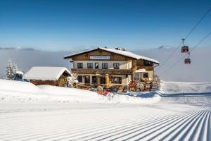 une maison dans la neige à côté d'une remontée mécanique dans l'établissement Berggasthof Höllenstein, à Wagrain