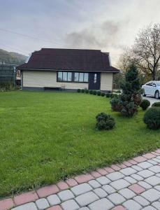a house with a green yard with a car at Садиба Анастасія in Sheshory