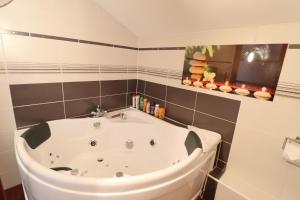 uma banheira branca na casa de banho com azulejos pretos em Le Lotus Blanc em Albertville