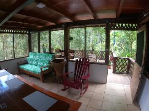a screened in porch with a couch and chairs at Finca Encanto Eco Lodge in Sierpe