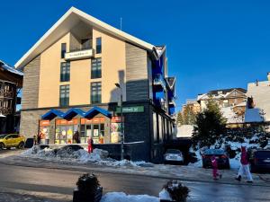 a building on a street with people walking in the snow at Centar Zlatibora, Vila Marina lux in Zlatibor