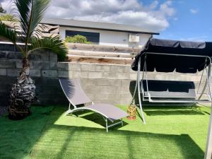 Les Avirons的住宿－COIN KREOL，院子里的椅子和雨伞和棕榈树