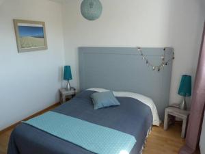 een slaapkamer met een blauw bed en 2 lampen bij Appartement avec piscine sur le Bassin d'Arcachon in Le Teich