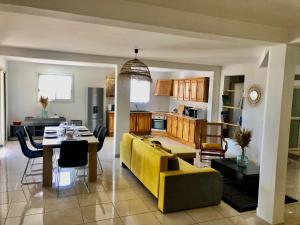 ein Wohnzimmer und eine Küche mit einem gelben Sofa und einem Tisch in der Unterkunft COIN KREOL in Les Avirons