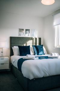a bedroom with a large bed with blue pillows at Freda House By Horizon Stays in Sunderland