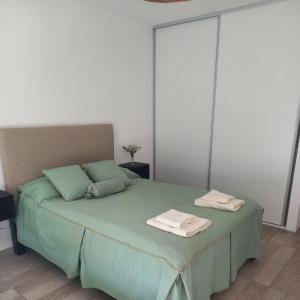 1 dormitorio con 1 cama verde y 2 toallas en EnSueños Tandil en Tandil