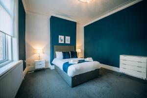 a bedroom with a bed and a blue wall at Freda House By Horizon Stays in Sunderland