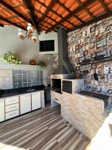 una cocina con armarios blancos y una pared de ladrillo en casa luz, en Foz do Iguaçu