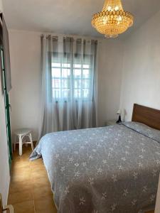 a bedroom with a bed and a chandelier and a window at Casa Armonía del sol in San Bartolomé de Tirajana