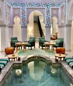 einen Pool in einer Hotellobby mit Stühlen und Tischen in der Unterkunft Riad Ksar Saad & Spa in Marrakesch