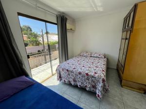 1 dormitorio con cama y ventana grande en casa luz, en Foz do Iguaçu