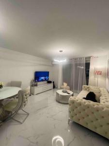 a living room with white furniture and a tv at Appartement luxury in Montpellier