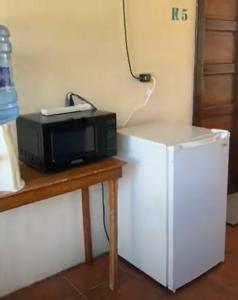 a microwave sitting on a table next to a refrigerator at Drift Inn Cayo in Santa Elena