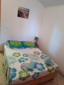 a bedroom with a bed with a colorful comforter and pillows at LES HAUTS DE FALAISE in Bouillante