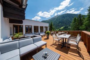a deck with a couch and tables and chairs at Hotel Karl Schranz in Sankt Anton am Arlberg